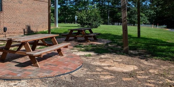 Outdoor patio with picnic tables and green lawn